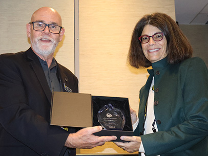 David Hagan presents Gisele Bennett with 2026 Distinguished Alumnus Award.