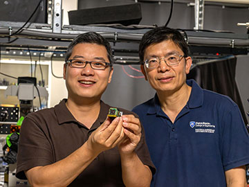 Two researchers holding a metasurface