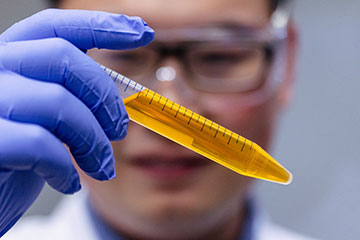 Researcher holding vial of yellow food coloring in solution