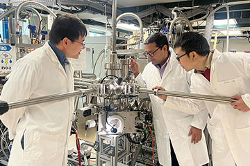 Three researchers working with a device in a lab