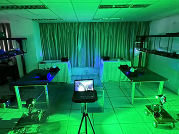 Green-lit room with lab tables and a computer screen