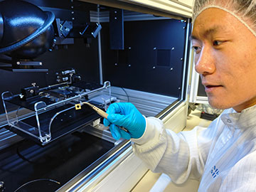 Researcher holding up sensor with tweezers