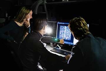 Three scientists looking at a screen