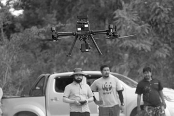 A team of men looking at a drone they are flying
