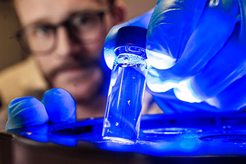 Researcher holding glowing blue tube