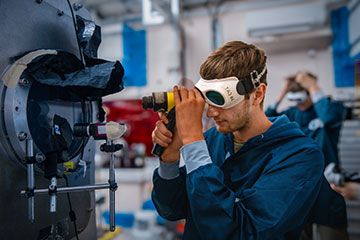 Researcher in goggles observing a laser beam in a lab